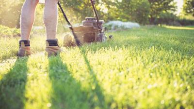 Persona cortando el césped con un cortacésped en un jardín