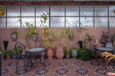Patio pequeño con sillas de forja y macetas de terracota