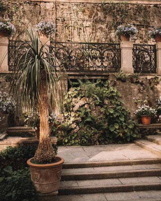 Jardín de estilo mediterráneo con macetas de terracota y balcón de hierro forjado