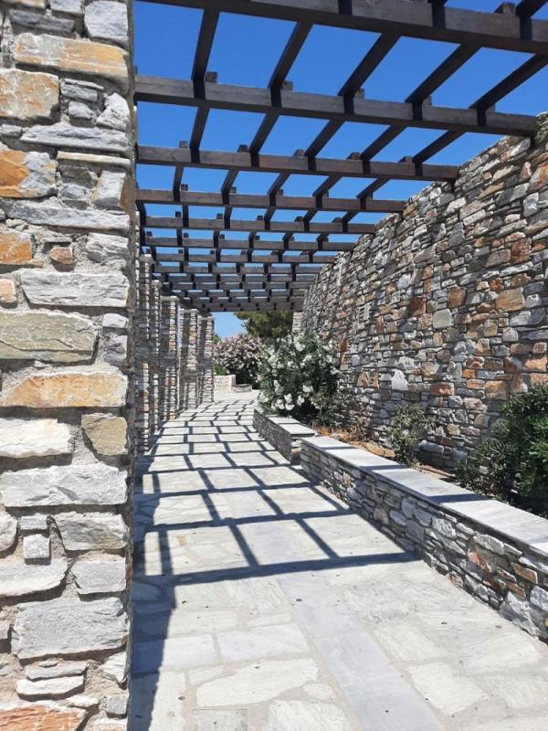 Pasillo de piedra rústica con pérgola en un jardín mediterráneo