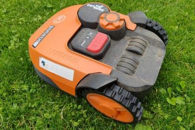 Robot cortacésped naranja visto de cerca sobre el césped