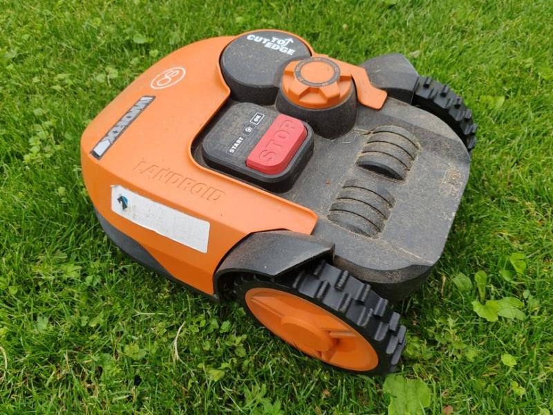 Robot cortacésped naranja visto de cerca sobre el césped