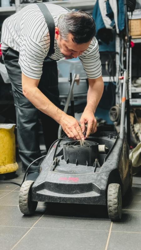 Técnico revisando un cortacésped eléctrico en un taller de reparación