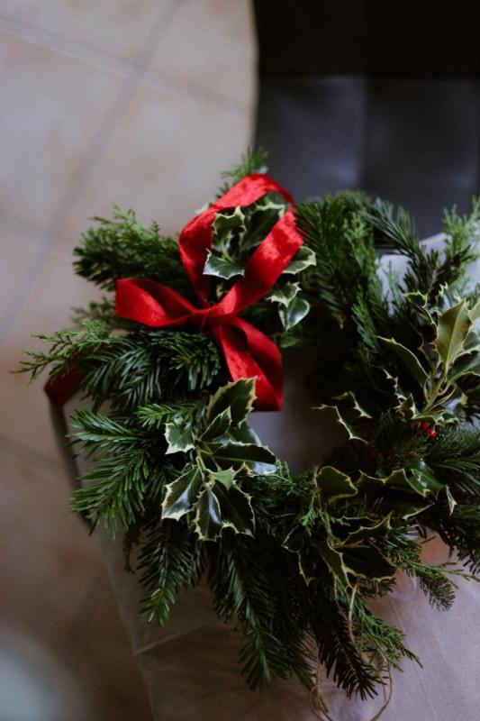 Corona de Navidad con acebo y lazo rojo