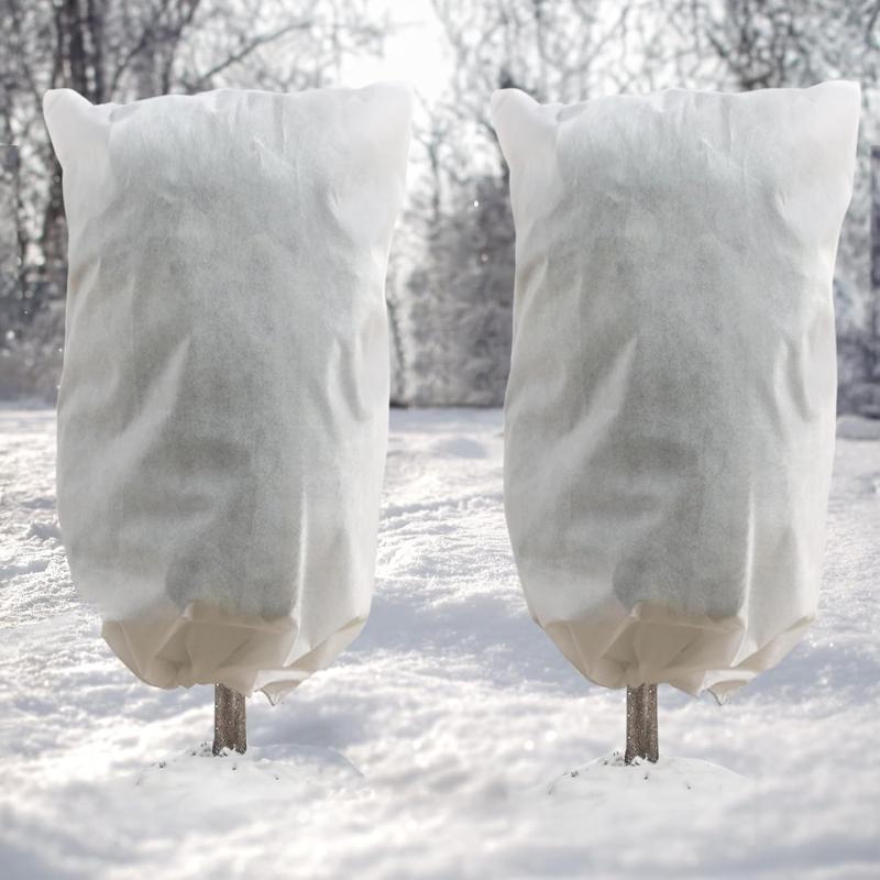 Dos fundas antiheladas DazSpirit con cordón cubriendo dos arbolitos en la nieve