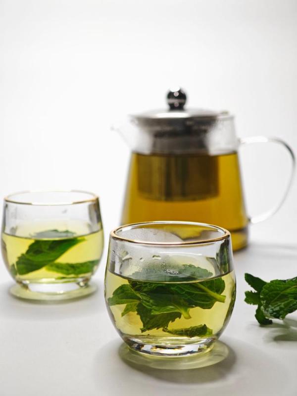 Infusión de menta fresca en vasos de cristal junto a una tetera